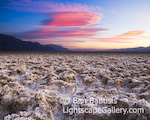 Devils Golf Course. Death Valley, California. The setting sun casts a red glow on wind swept clouds over Death Valley's eerie landscape. In the foreground is Devil's Golf Course, a thick collection of natural salt, the surface of which is sharpened into jagged points by the forces of wind and rain.  Ben Babusis, Lightscape Gallery.
