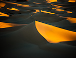 Black and Yellow. Death Valley, CA. Early morning magic light infiltrates the Stovepipe Wells Dunes in Death Valley, creating a contrasty landscape of blacks and yellows.  Ben Babusis, Lightscape Gallery.